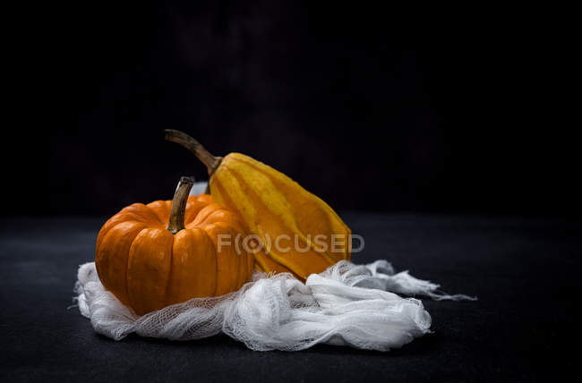 Fresh pumpkins on white cloth on black background — Stock Photo