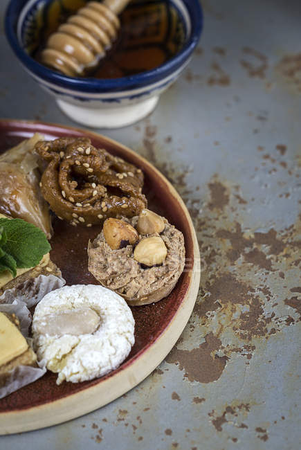 Dulces típicos marroquíes con miel y almendras en plato de madera sobre una superficie gris malhumorado - foto de stock
