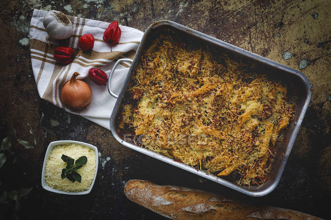 Baked macaroni with cheese and chorizo in baking pan on rustic table with ingredients — Stock Photo