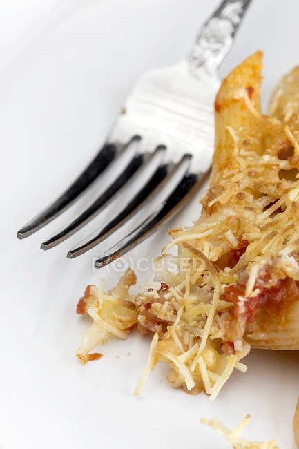 Крупным планом макароны с сыром и чоризо на белой тарелке с вилкой — стоковое фото