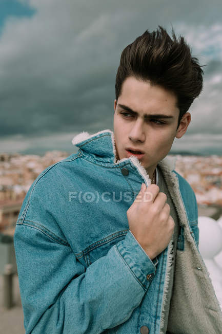 Retrato de jovem adolescente em casaco de ganga elegante em pé no fundo da cidade — Fotografia de Stock