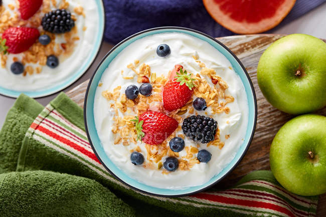 Сніданок з йогуртом та ягодами на столі з інгредієнтами — стокове фото