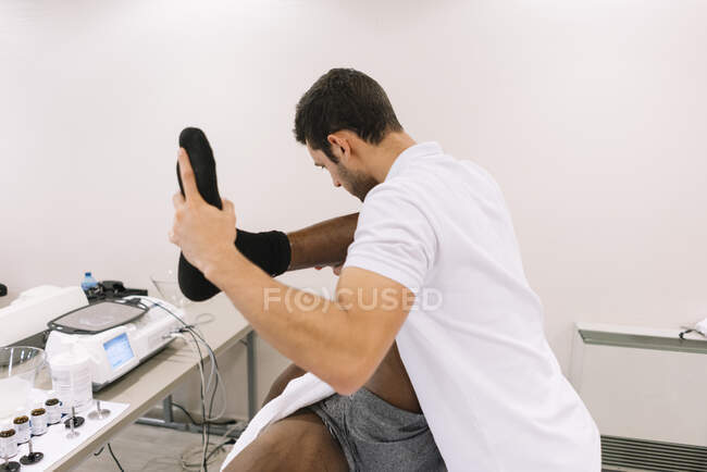 El fisioterapeuta que trata a un hombre usando equipos para radioterapia - foto de stock
