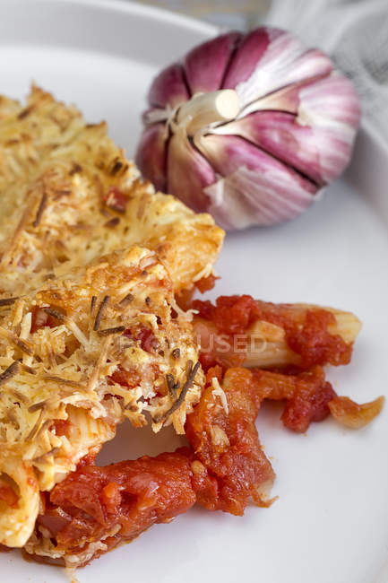 Close-up of Macaroni with cheese and chorizo on white plate with garlic bulb — Stock Photo