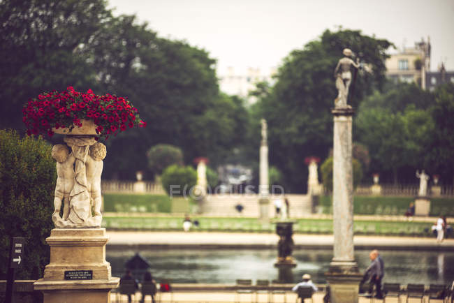 Площадь с древними памятниками и людей, сидящих рядом с прудом, Париж, Франция — стоковое фото