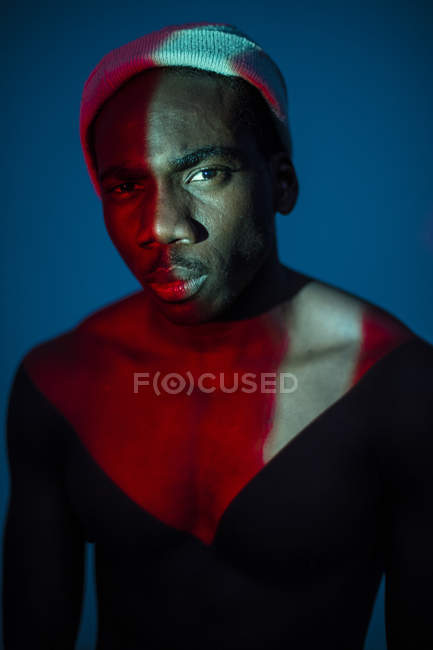 Этнический мужчина, стоящий со светлыми пятнами на теле и смотрящий в камеру — стоковое фото