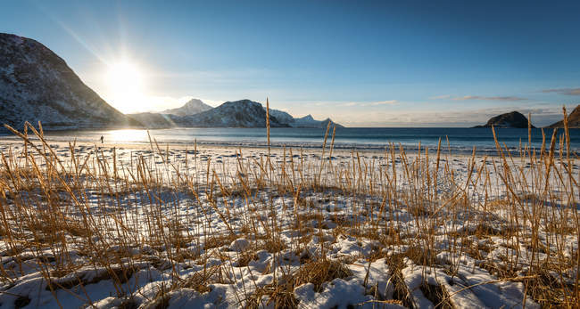 Vista pitoresca de montanhas nevadas e mar em backlit — Fotografia de Stock