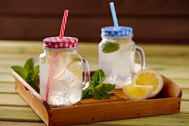 Дерев'яний лоток зі скляними чашками охолоджуючого лимонаду з лимонаду та м'яти — стокове фото