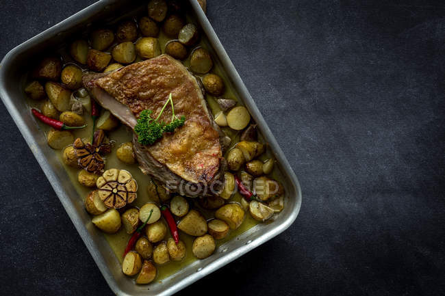 Cordeiro assado com batatas em assadeira em fundo cinza — Fotografia de Stock