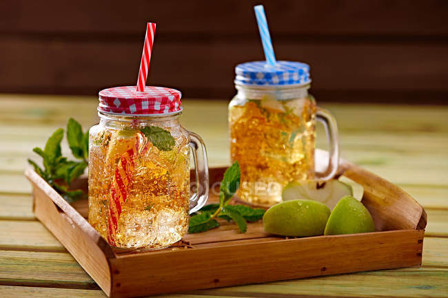 Bandeja de madera con copas de vidrio de limonada fría hecha de lima y menta - foto de stock