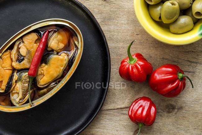 Red peppers and canned mussels on black plate — Stock Photo