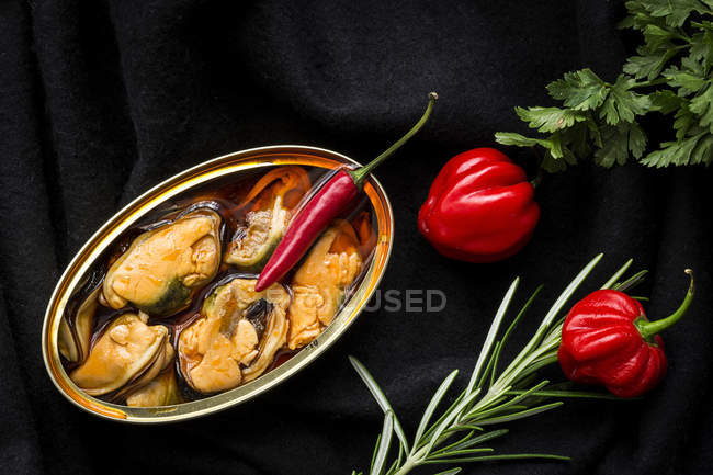 Red peppers and canned mussels on black fabric — Stock Photo
