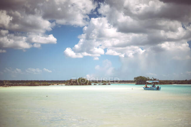 Люди пливуть маленьким човном у хмарний день, відпочиваючи в мексиканському каріббові. — стокове фото