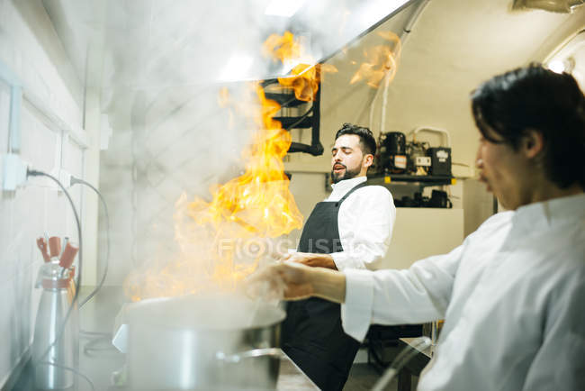 Cook making flambe in restaurant kitchen — Stock Photo