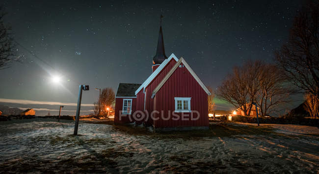 Cabaña roja de madera en valle nevado por la noche - foto de stock