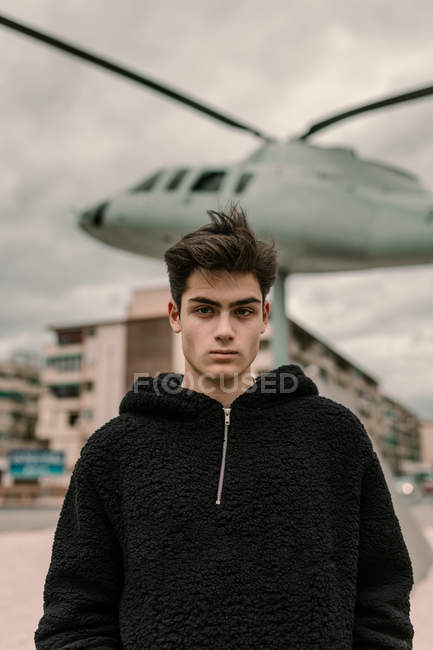 Handsome young man standing at helicopter monument on city street — Stock Photo