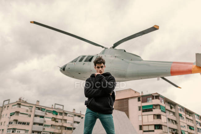 Красивий молодий чоловік стоїть біля пам'ятника вертольоту на міській вулиці — стокове фото