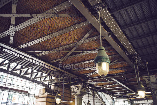 Iron construction on ceiling of old building for renovation with hanging lamps — Stock Photo