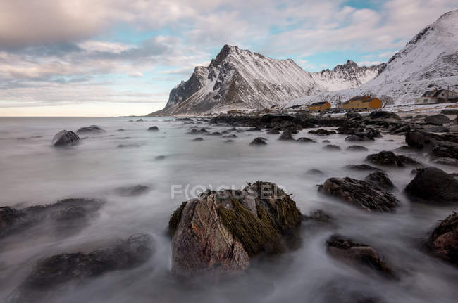 Rocce lisce nel flusso di acqua e montagne rocciose innevate sullo sfondo — Foto stock