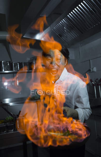 Cuoco eccitato facendo un flambe in cucina ristorante — Foto stock