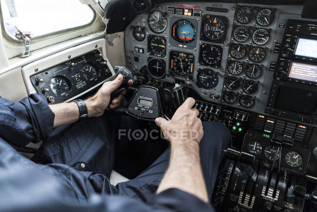 Неузнаваемый человек в наушниках пилотирует самолет? в одиночку, сидя в кабине современного самолета — стоковое фото