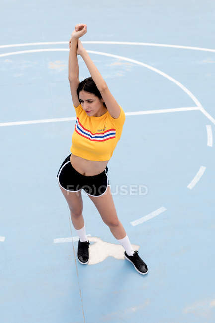 Mince jeune femme en vêtements de sport debout sur le terrain de sport bleu — Photo de stock