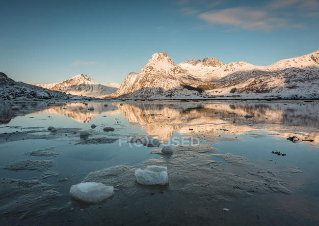 Camada de gelo rachado na água com montanhas sob o céu azul — Fotografia de Stock