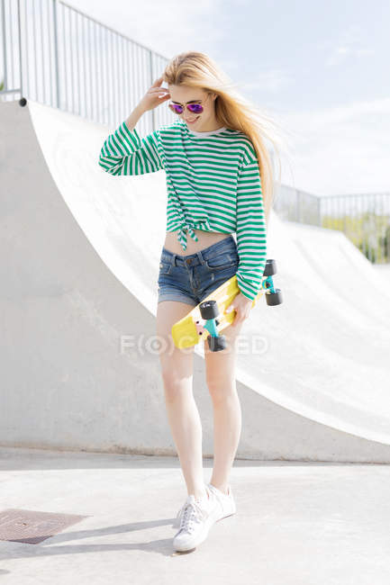 Blonde girl walking with penny board in skate park — Stock Photo