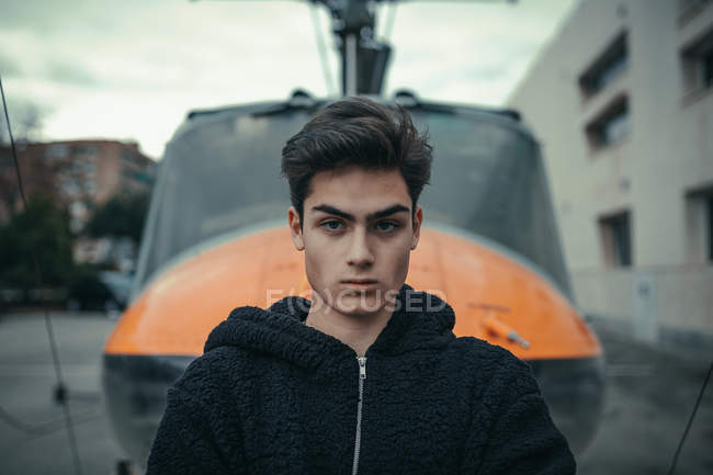 Young man standing with helicopter monument on background — Stock Photo