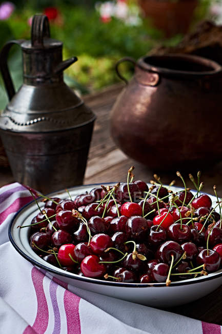 Cerejas frescas em tigela de metal na mesa de madeira marrom — Fotografia de Stock