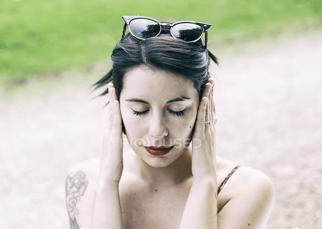 Jeune femme hipster assis à l'extérieur et couvrant les oreilles avec les mains — Photo de stock