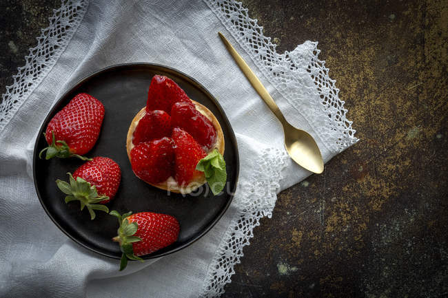 Deliciosa sobremesa cheia de creme e morangos frescos na placa preta no guardanapo branco — Fotografia de Stock
