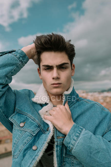 Portrait of young teenager in stylish denim jacket standing on background of city — Stock Photo