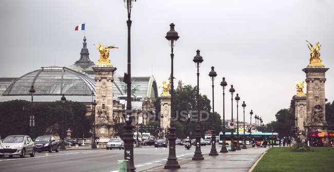 Alexander III ponte com lanternas em fileira e ouro coberto estátuas no fundo do Grand Palais. Paris, França — Fotografia de Stock