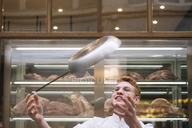 Chef cuisinier dans des verres et robe blanche vomissant poêle à frire travaillant dans le restaurant. — Photo de stock