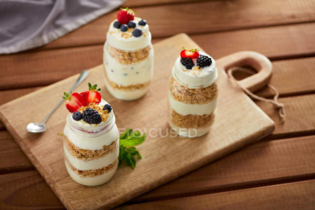 Vasi di vetro con muesli e yogurt su tavola di legno — Foto stock