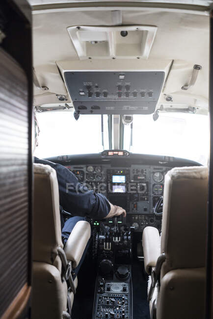 Un homme méconnaissable dans un casque pilotant un avion seul assis dans le poste de pilotage d'un aéronef moderne — Photo de stock