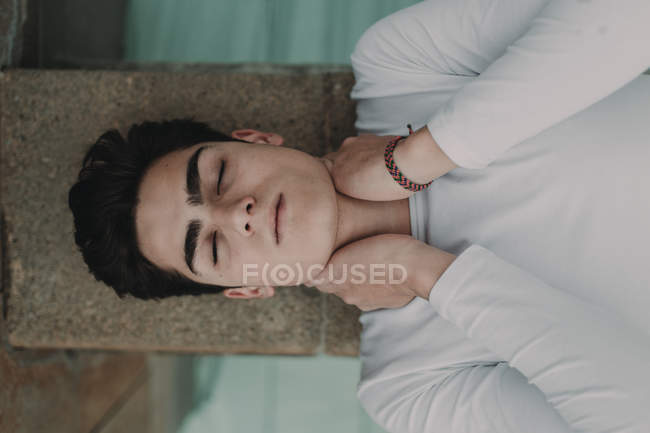 Jeune homme beau couché sur un mur de béton — Photo de stock