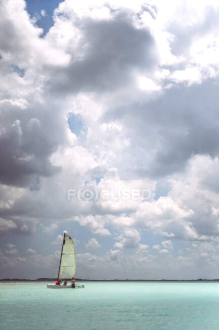 Люди пливуть маленьким човном у хмарний день, відпочиваючи в мексиканському каріббові. — стокове фото