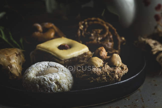 Close-up of Typical Moroccan sweets with honey and almonds on black platter — Stock Photo
