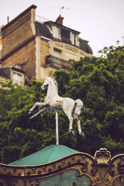 Primer plano de la estatua del caballo blanco en la azotea verde sobre el fondo de los árboles y el edificio en París, Francia - foto de stock