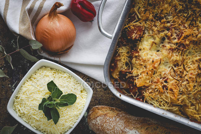 Печеные макароны с сыром и чоризо в кастрюле на деревенском столе с ингредиентами — стоковое фото