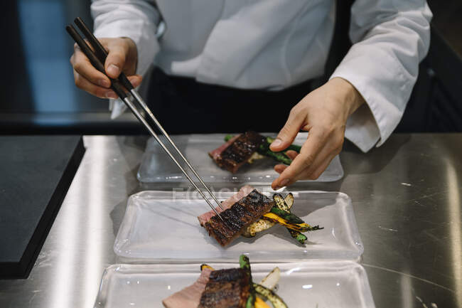 La cocina del chef en el restaurante prepara los platos con palillos - foto de stock