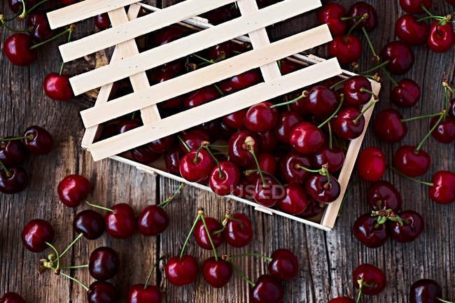 Wooden box of delicious ripe cherries on brown wood — Stock Photo