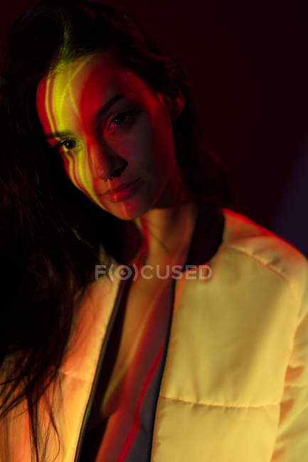 Красивая молодая женщина в белой куртке со светлыми пятнами на лице, смотрящая в камеру — стоковое фото