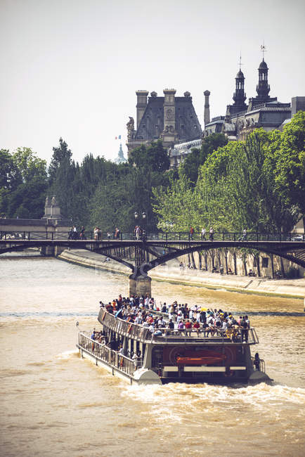 Катер, плывущий по реке Сена на фоне зеленых деревьев и Лувра, Париж, Франция — стоковое фото