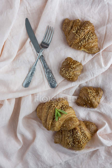Hausgemachte gebackene Croissants auf weißem Stoff mit Gabel und Messer — Stockfoto