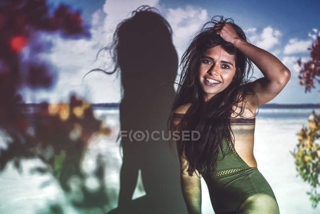 Портрет молодой женщины в купальнике, позирующей в студии на фоне пляжа — стоковое фото