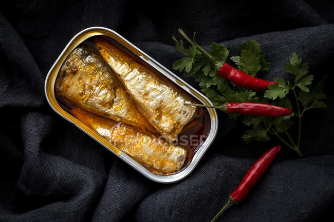 Conserve di sardine con peperoni rossi freschi e prezzemolo su tessuto nero — Foto stock