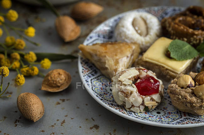 Dolci tipici marocchini con miele e mandorle su piatto di legno su superficie grigio squallido — Foto stock